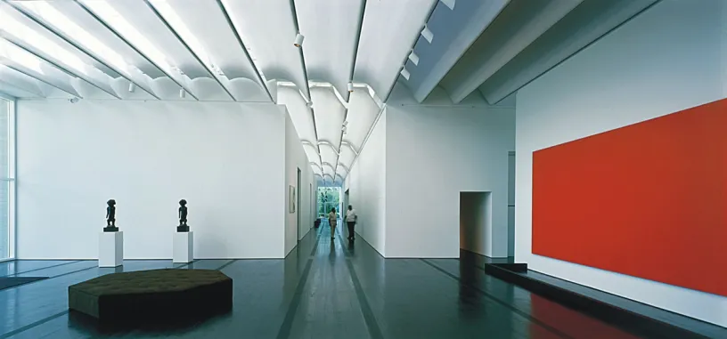 a long hallway in a museum with a red wall