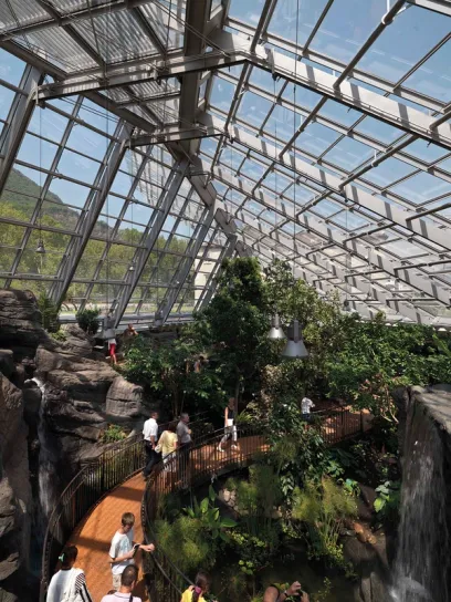 a group of people are walking through a large glass building