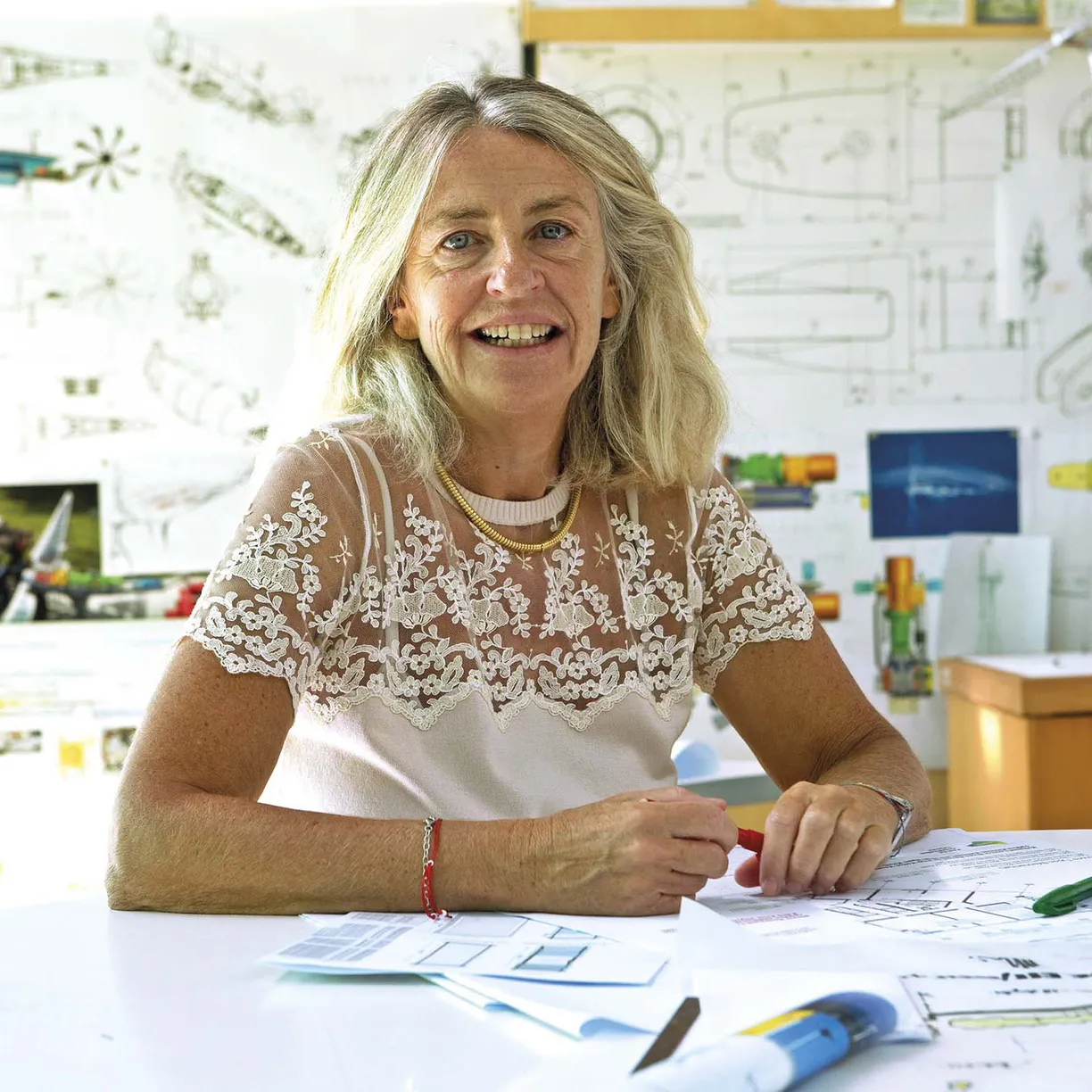 A woman wearing a white lace top sits at a desk