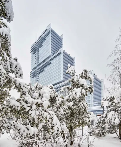 A snowy forest with a tall building in the background