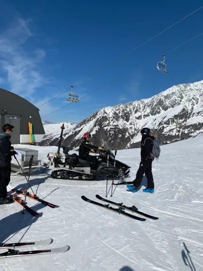 A gray ski gondola cabin with open doors and a white box inside, at a mountain loading station.