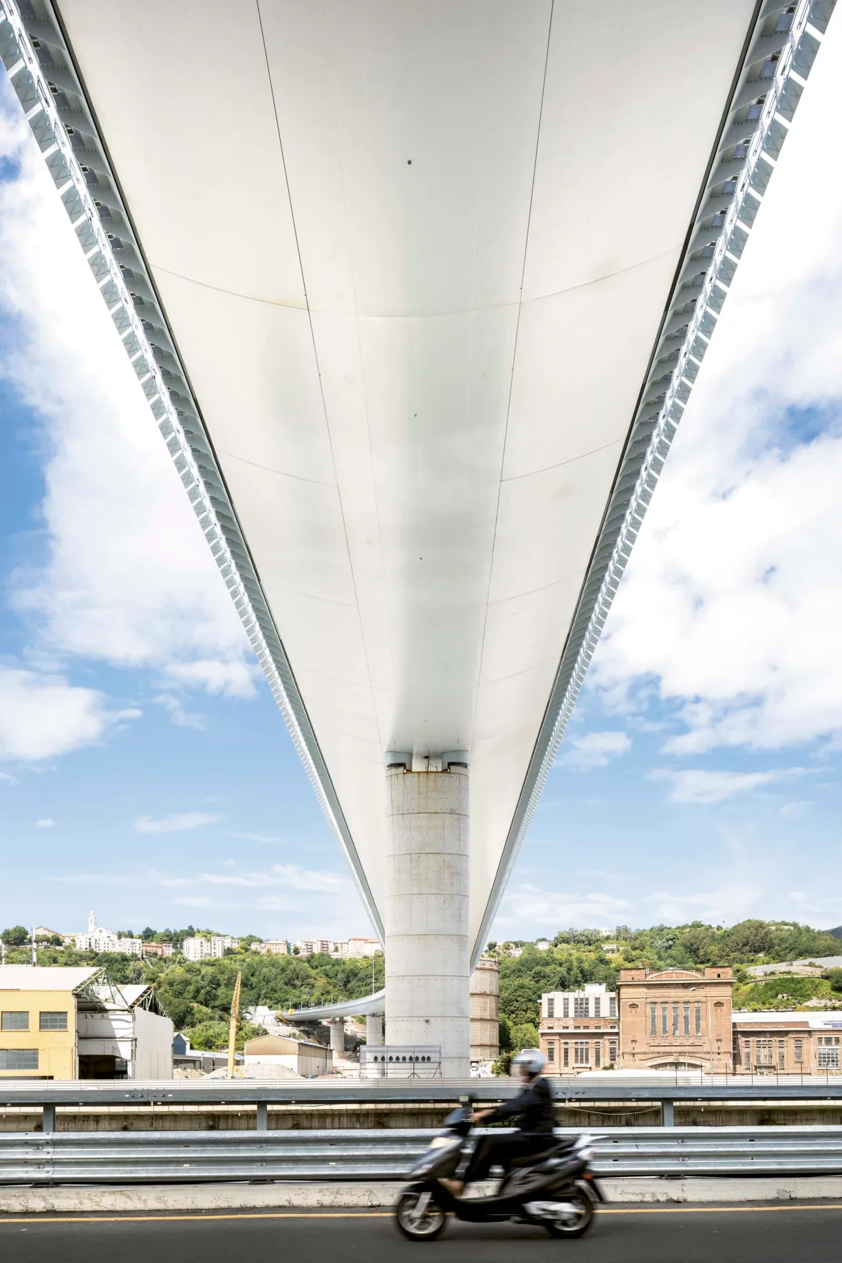 a person riding a scooter under a bridge