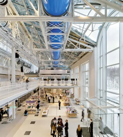 A group of people are standing in a large building with lots of windows