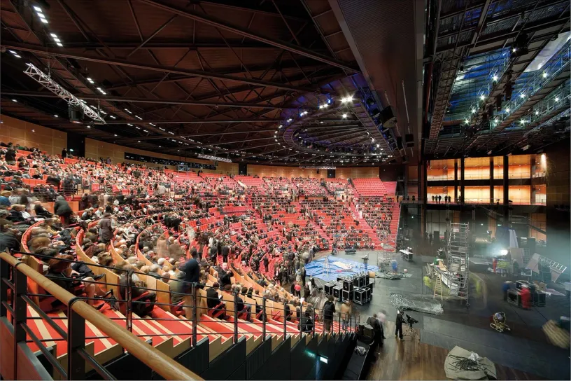 A large auditorium filled with people sitting in red seats
