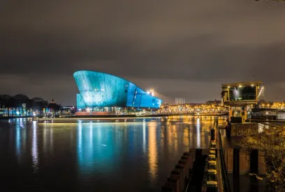 A large building is lit up at night next to a body of water