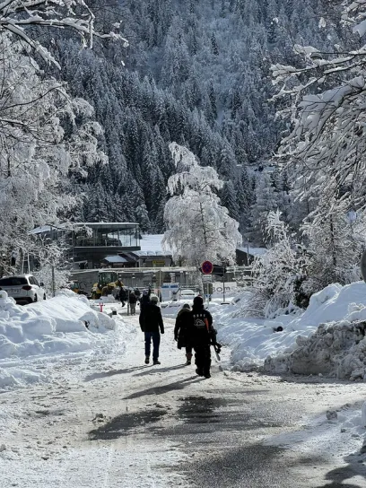 a group of people are walking down a snow covered road