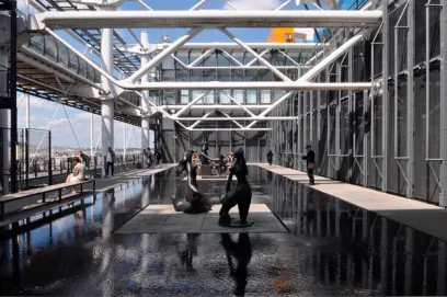 A group of people are standing around a fountain in a large building
