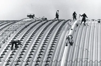 a group of construction workers are working on the roof of a building .