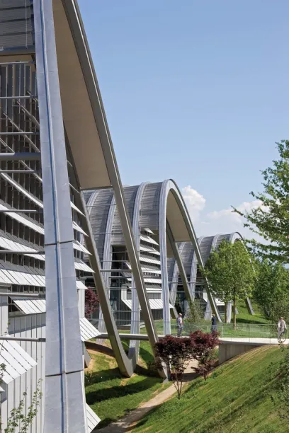 A building with a curved roof is surrounded by grass and trees
