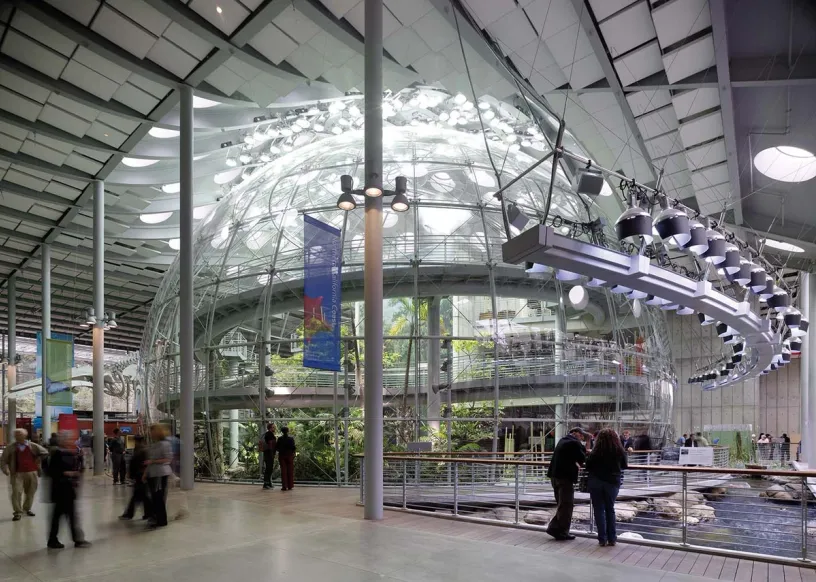 a group of people are standing in front of a large glass dome .