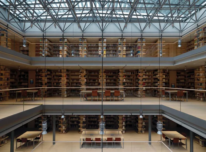 a large library with lots of bookshelves and tables and chairs .