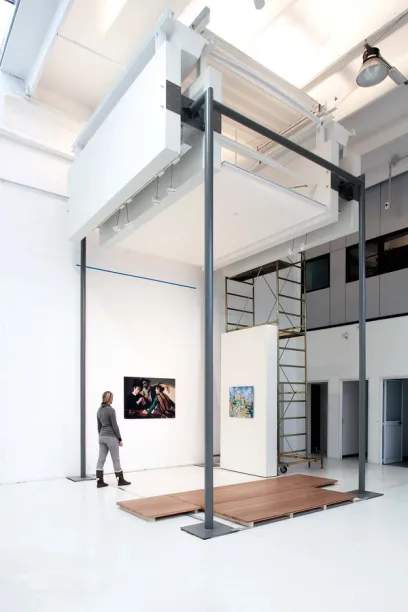 a woman stands in a room with a painting on the wall