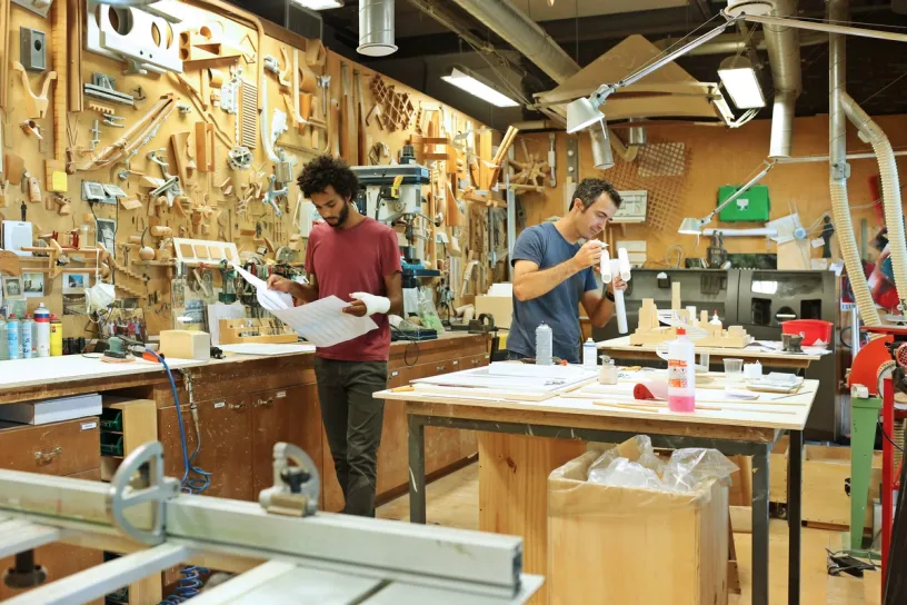 two men are working in a woodworking shop .