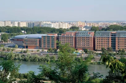 A large building is sitting next to a river in the middle of a city