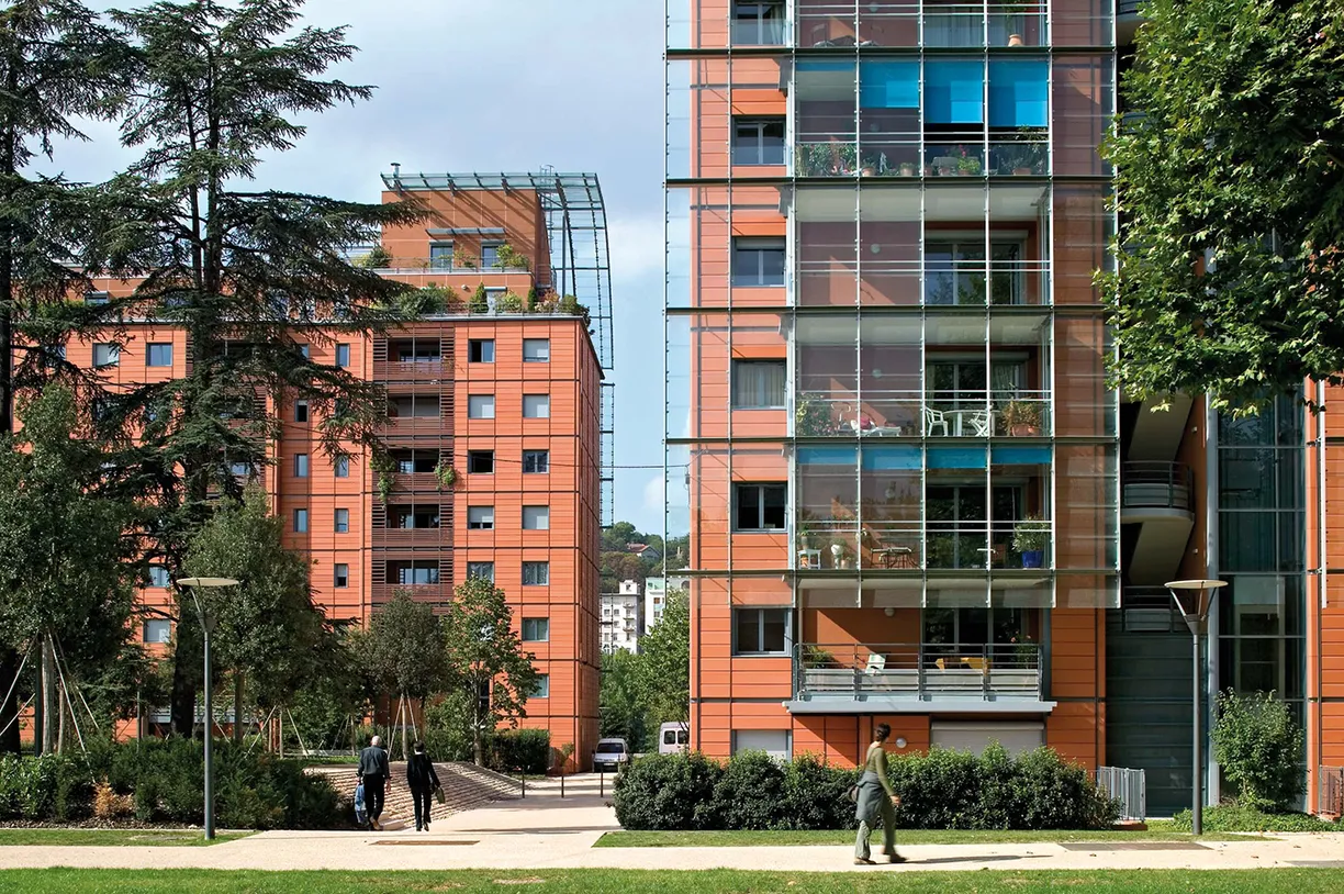 A man is walking in front of a tall building with a lot of windows