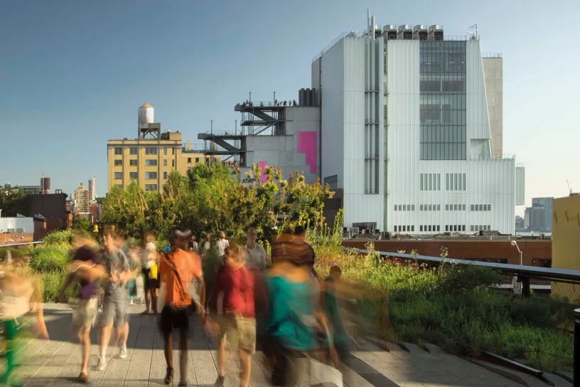 A group of people are walking down a sidewalk in front of a building