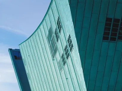 A green building with a curved roof and a blue sky in the background