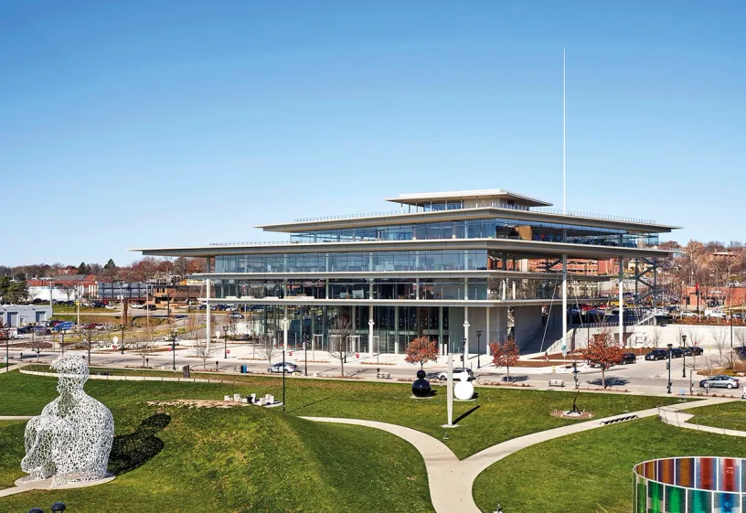 A large building with a lot of windows is sitting in the middle of a park