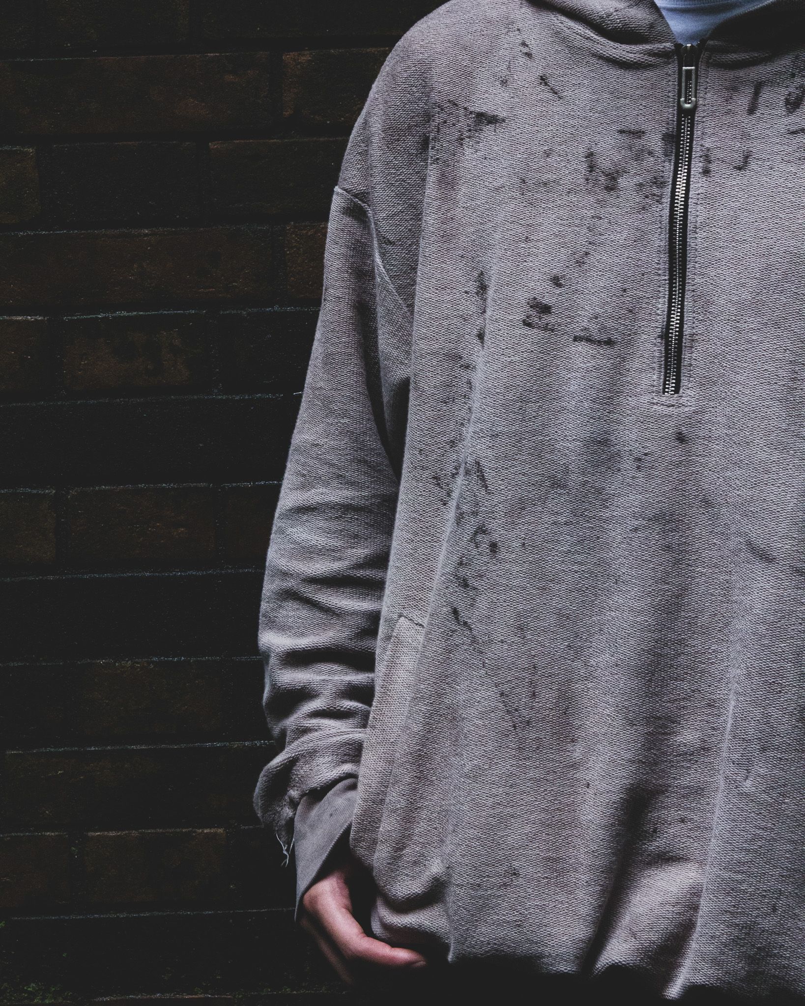 Model in the rust-dyed hoodie, hood up, in a tunnel at night