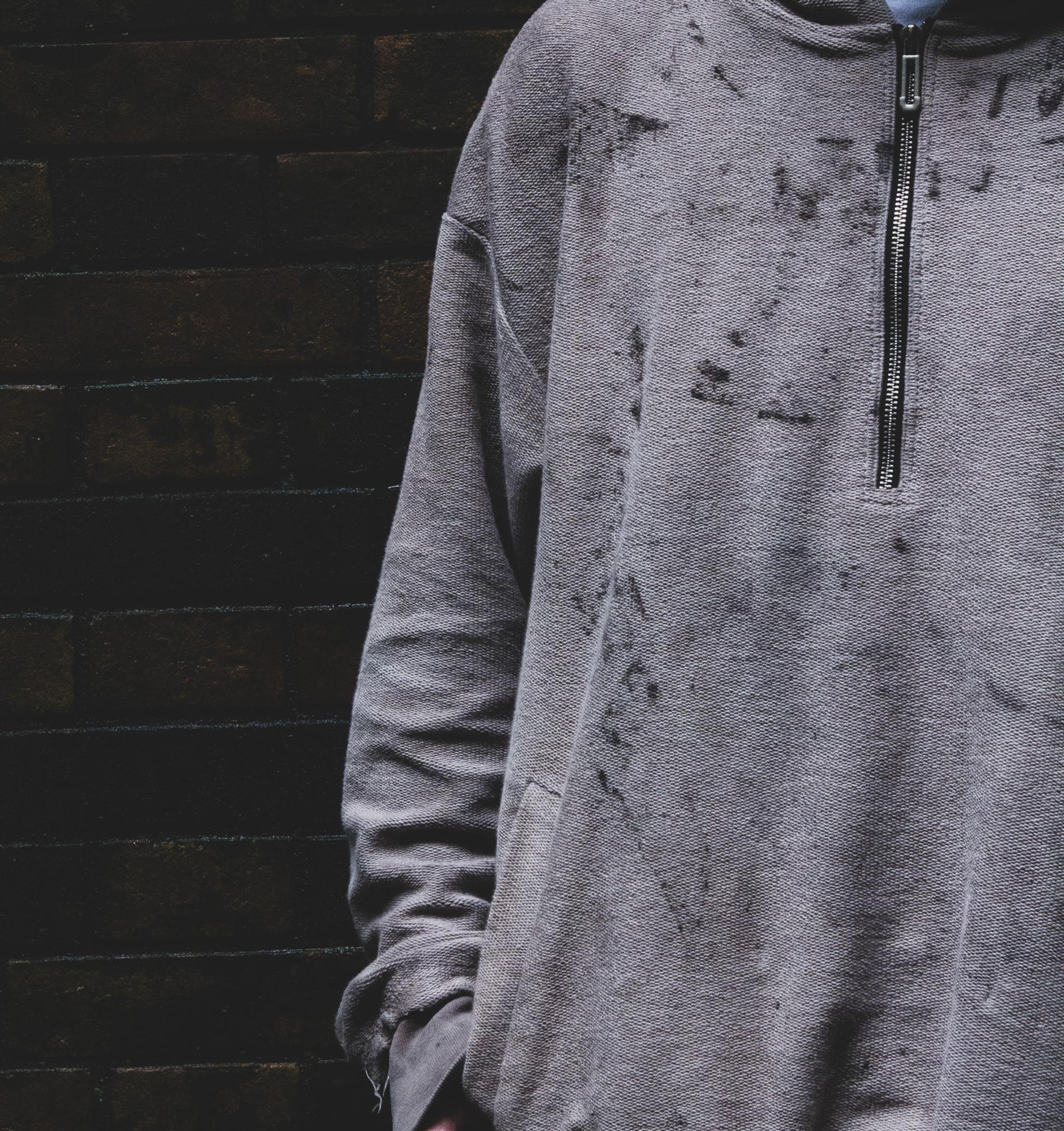 Model in the rust-dyed hoodie, hood up, in a tunnel at night