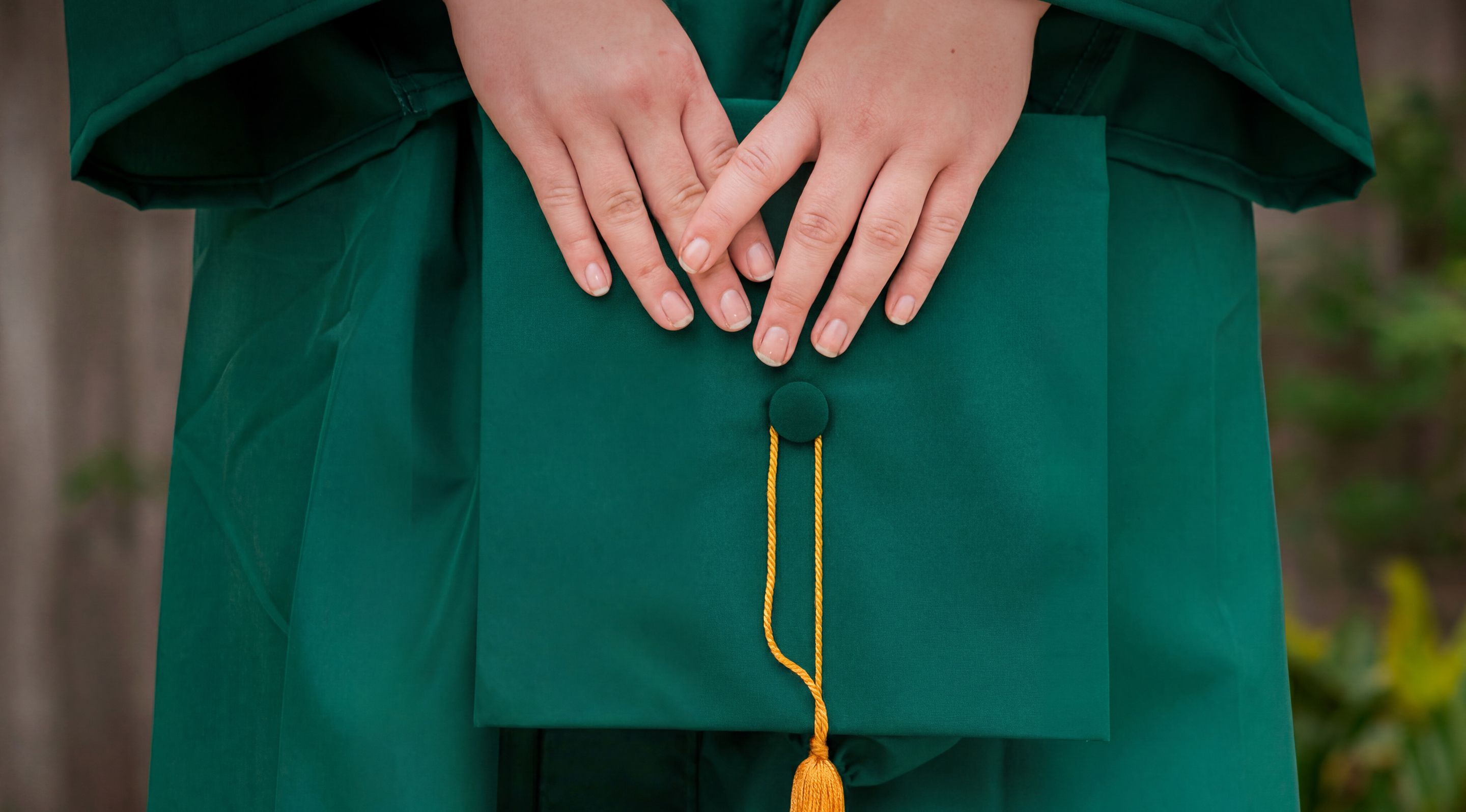 A woman's hands holding a graduation cap.