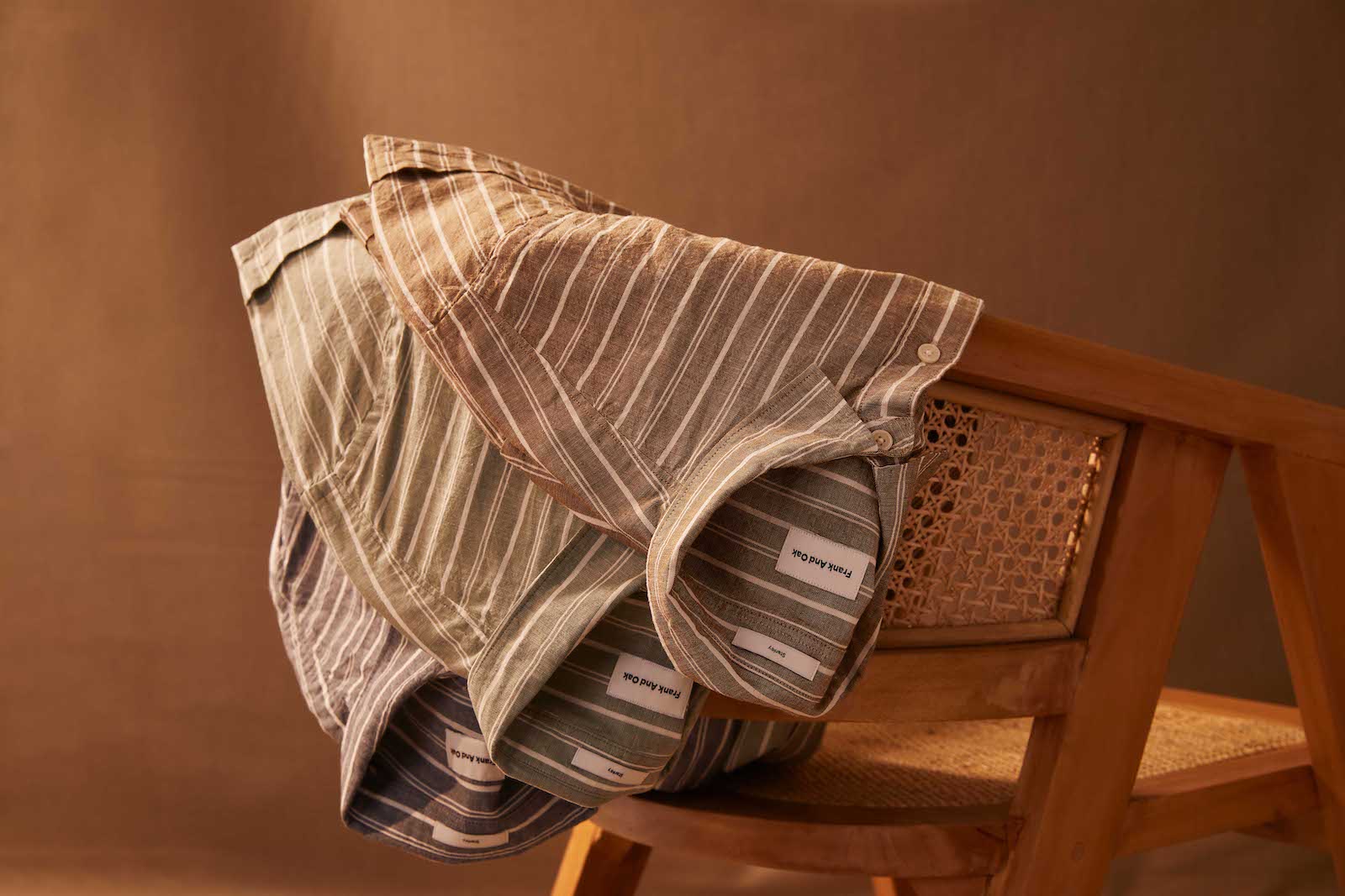 Three Frank and Oak button up tees draped over a chair