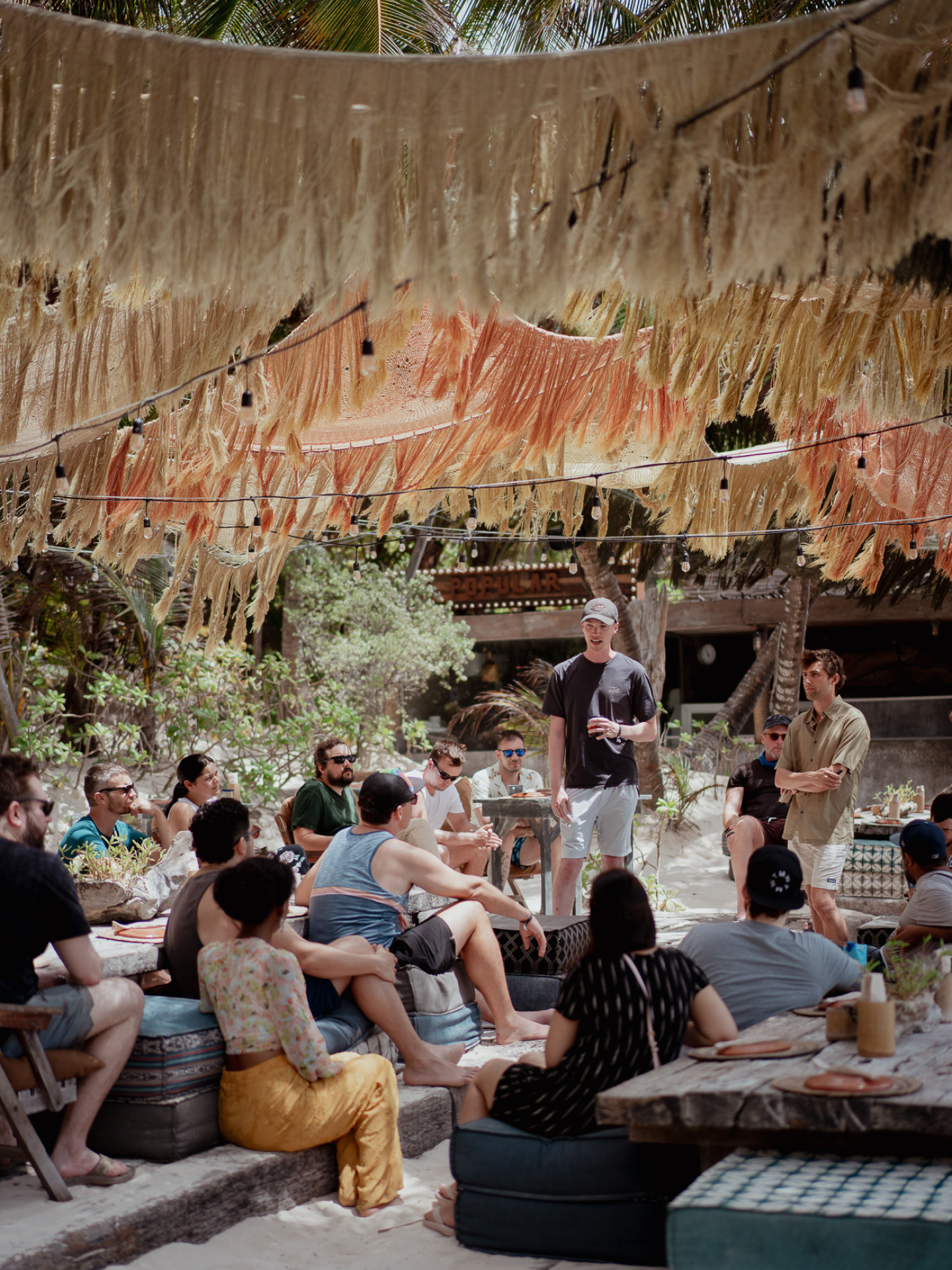 Someone team members in a workshop at Nomad Tulum, on cushions and under a canopy on the sandy beaches of Mexico