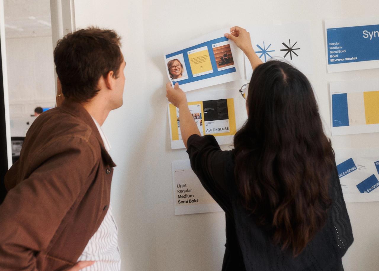 Sarah and Milo pinning brand guidelines to wall