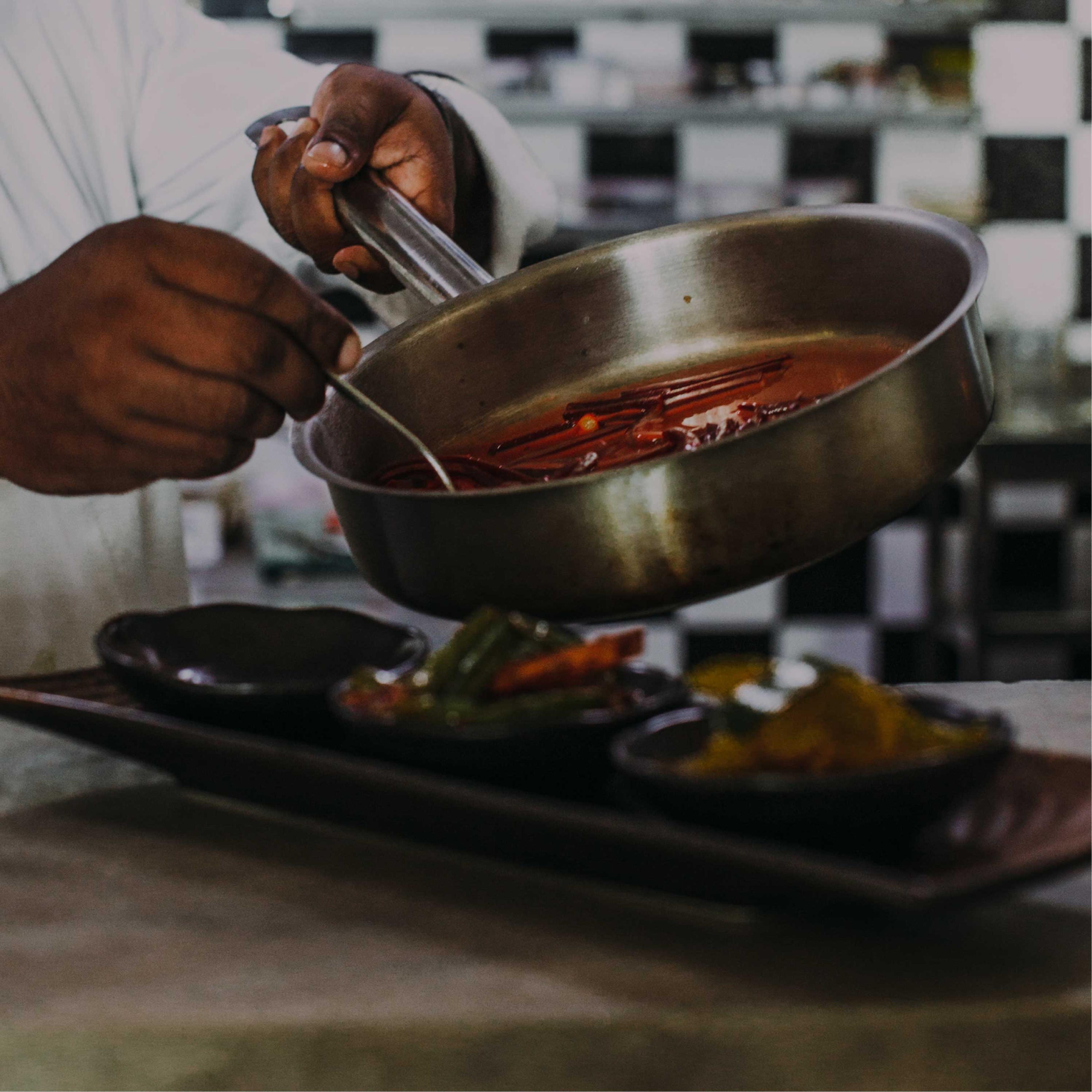 A chef pouring a glaze over plated appetizers