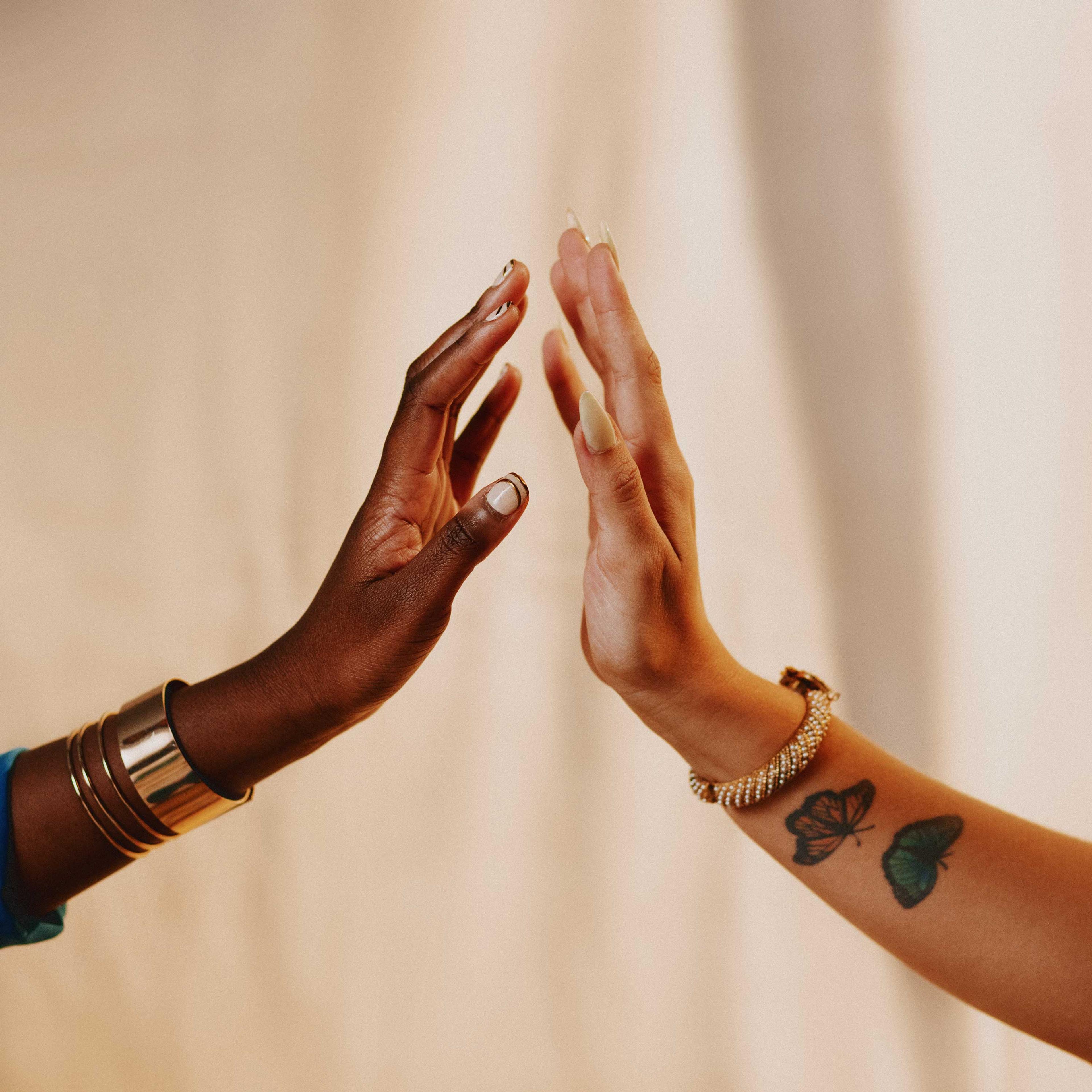 Two brown-skin hands coming together to visually represent reflection. 