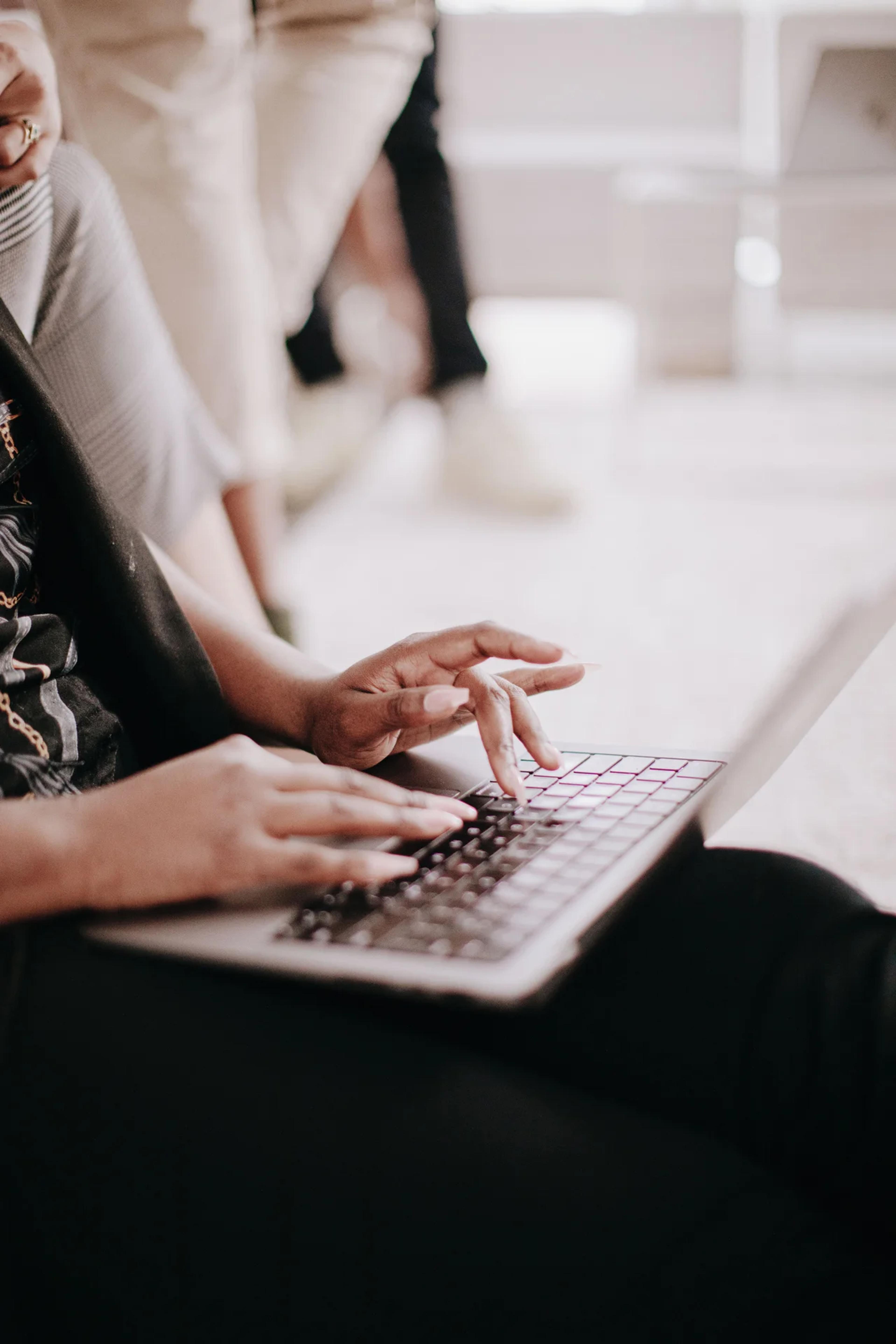 Black hands typing on a laptop.