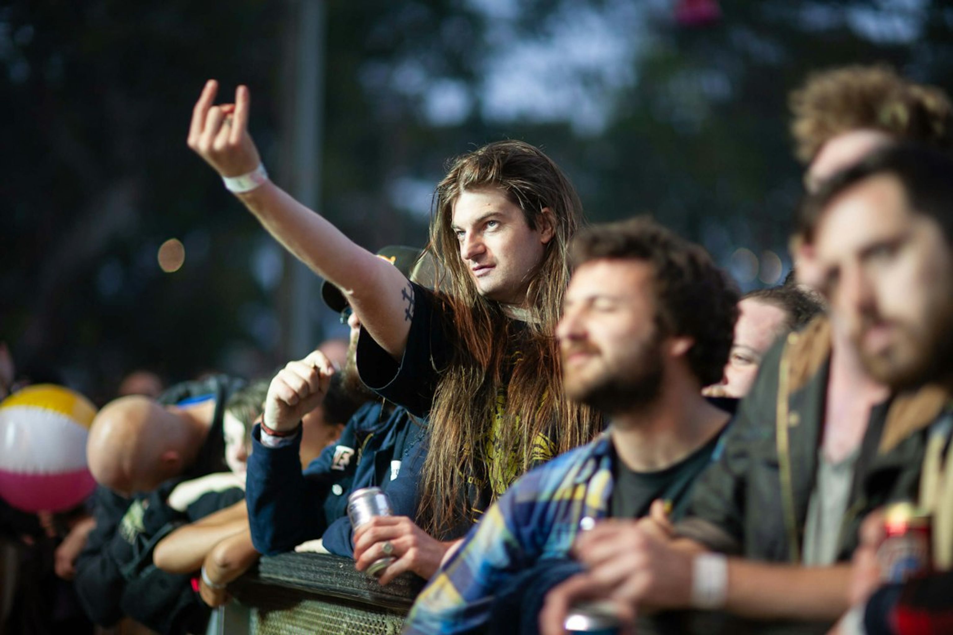 Festival crowd, a long-haired man pointing skyward among friends