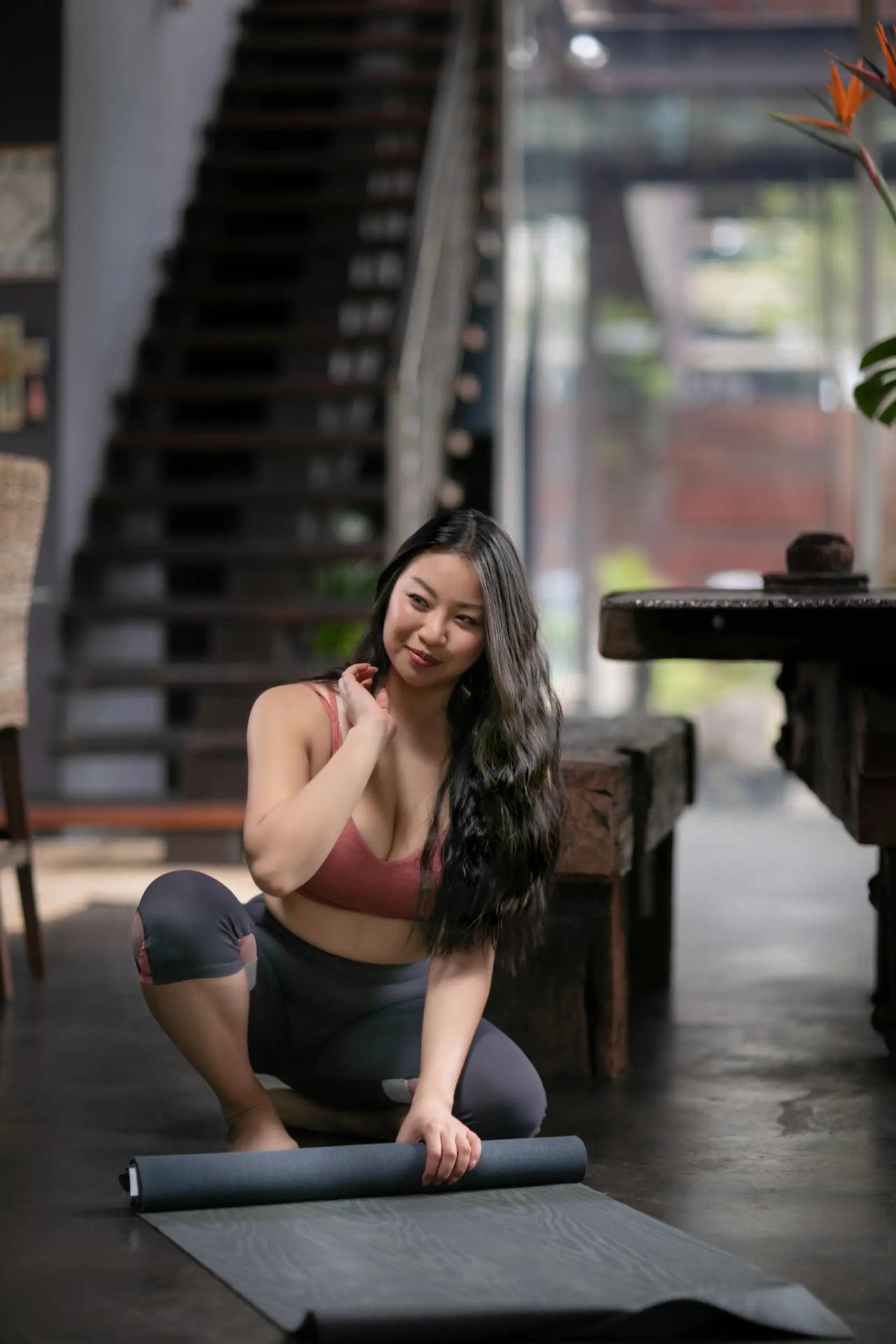 Woman stretching on a yoga mat at the foot of a staircase