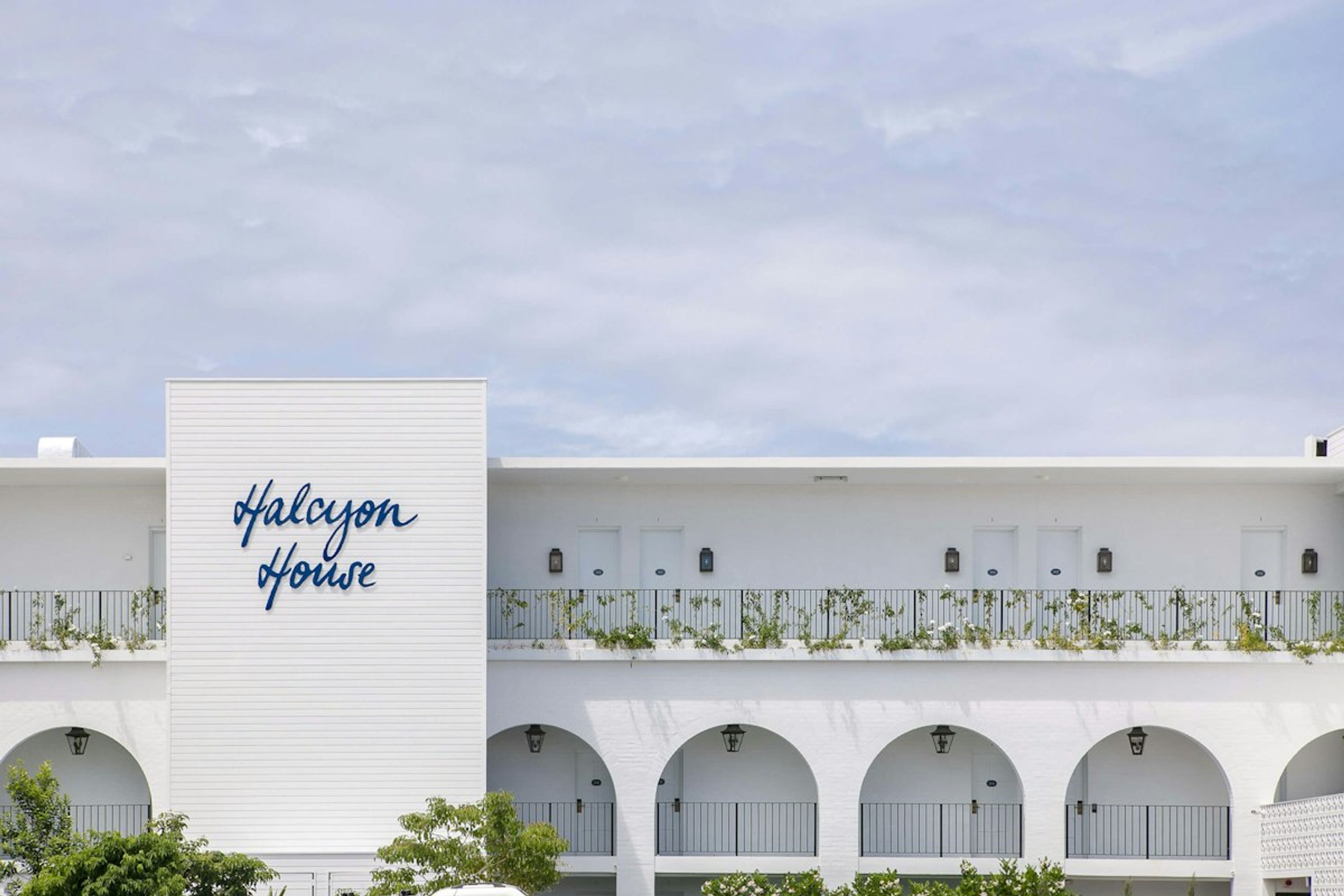 White hotel facade with arched balconies and Halcyon House signage under a pale sky
