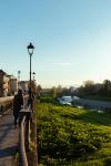 A tree-lined park path in Parma at dusk with a street lamp