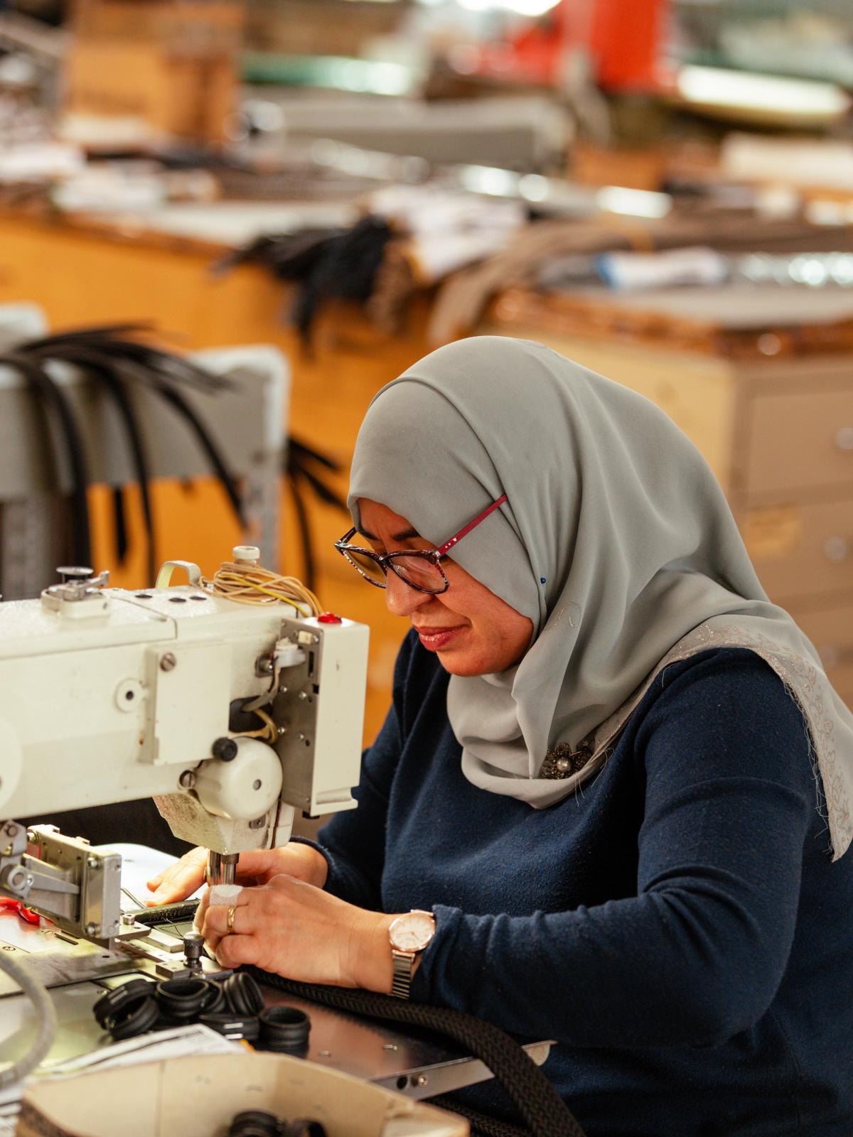 A seamstress working at a sewing machine in the Anderson's workshop