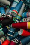 A pile of yarn cones in many colours