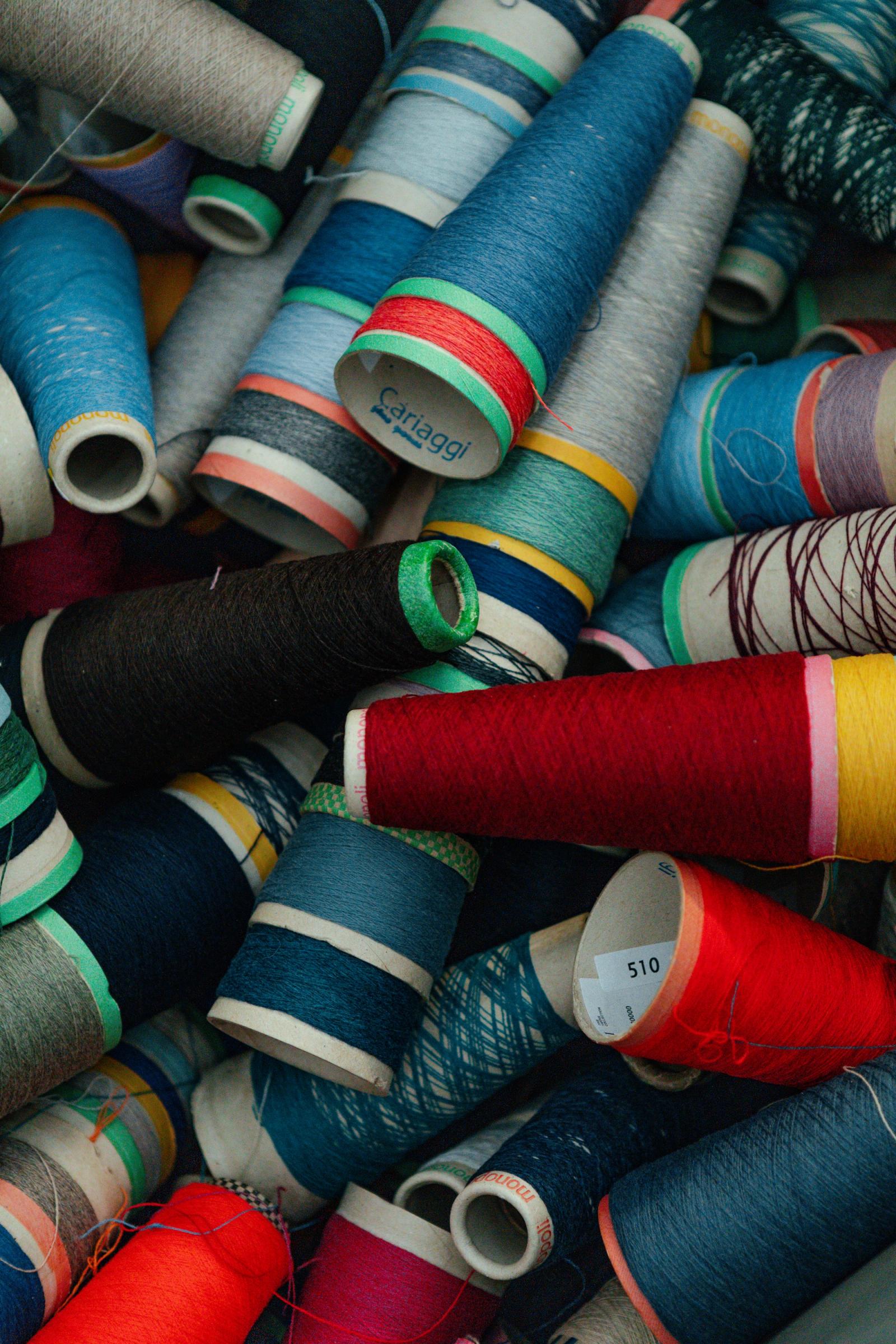 A pile of yarn cones in many colours