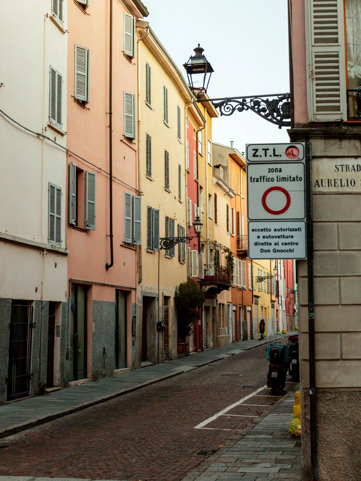 A narrow street in Parma lined with pastel-coloured buildings