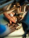 Close-up of hands assembling a leather belt at a workshop machine