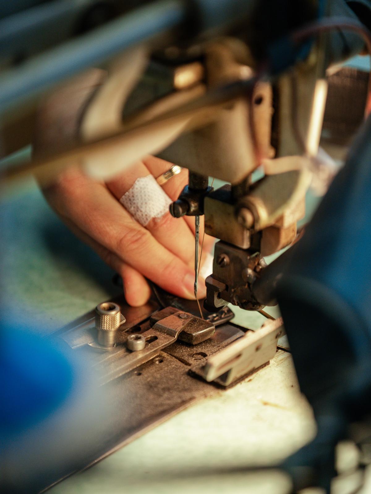 Close-up of hands assembling a leather belt at a workshop machine
