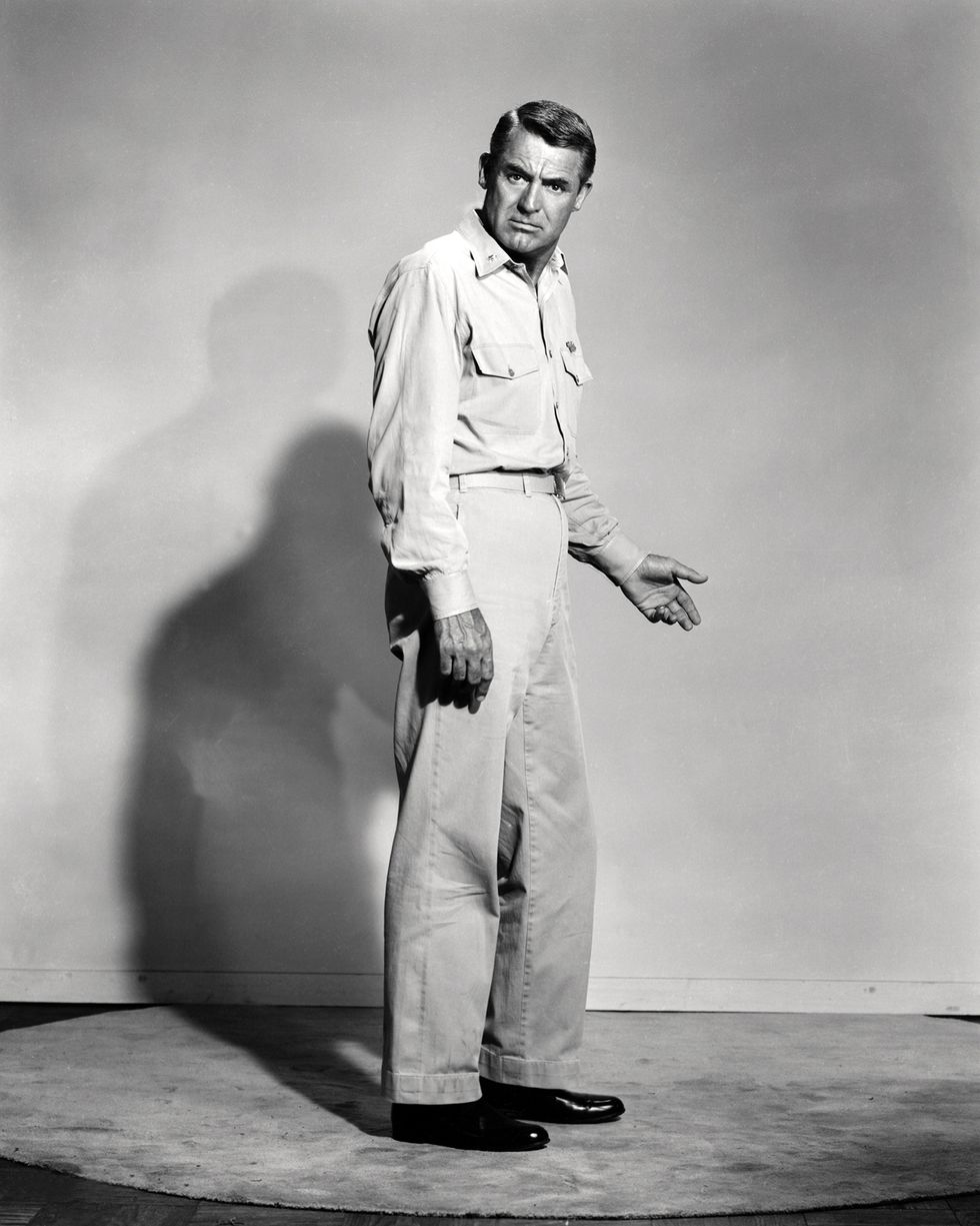 Cary Grant in a light shirt and trousers against a studio backdrop