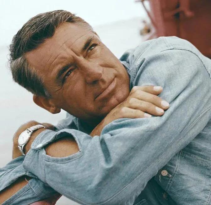 Cary Grant in a denim shirt with his arms crossed