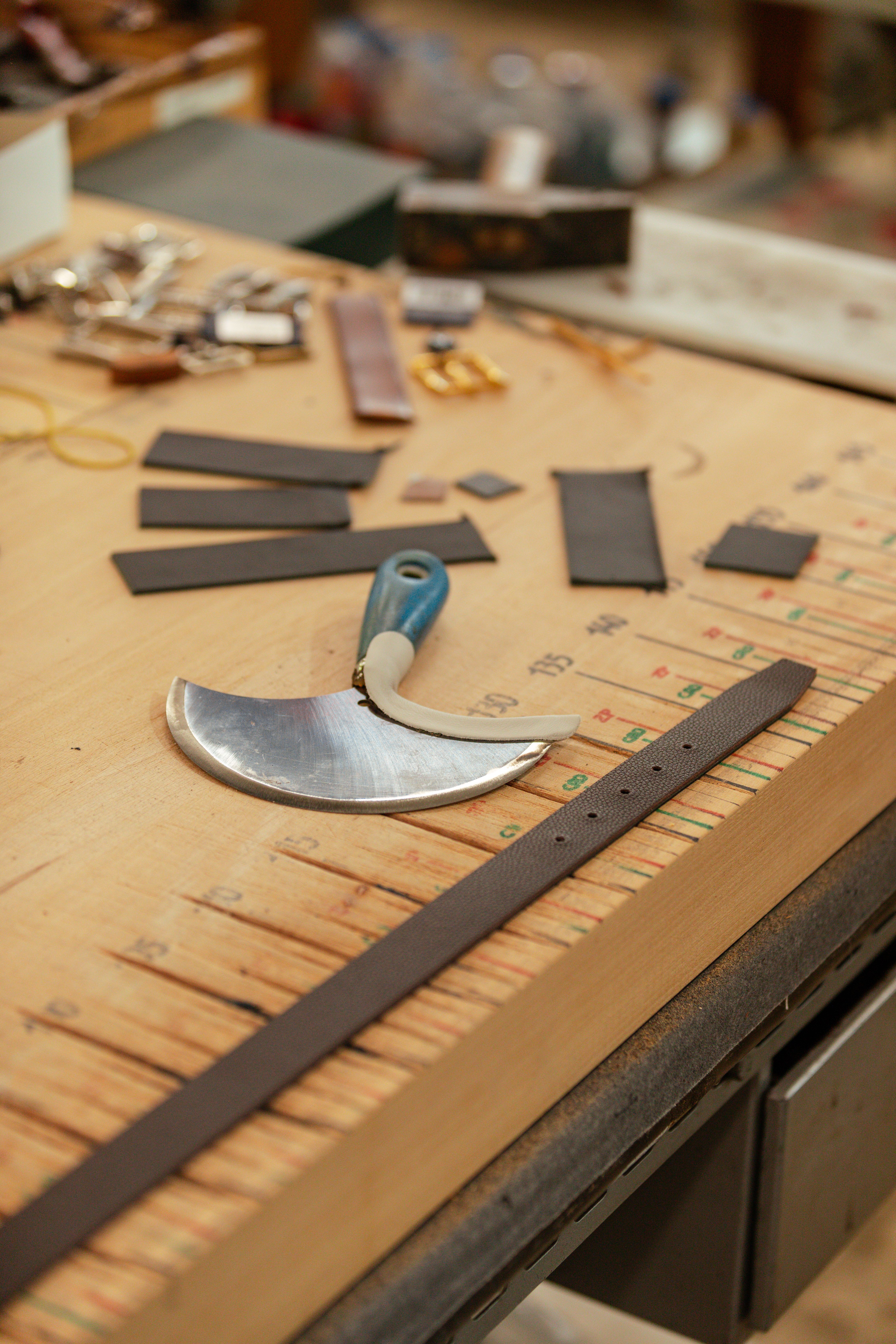 Leather strips and a half-moon leather knife on a workbench