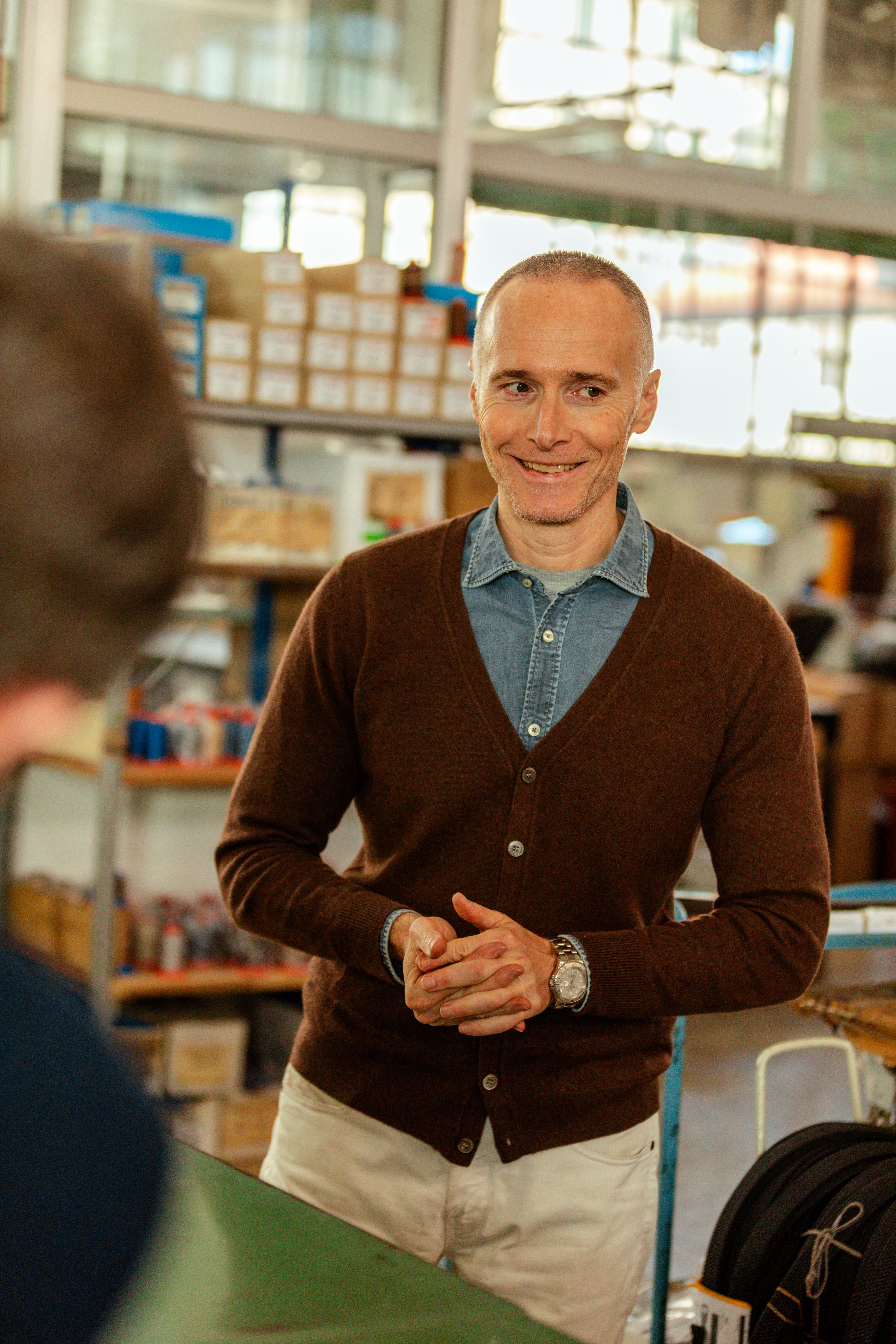 A smiling craftsman in a brown cardigan in the Anderson's workshop