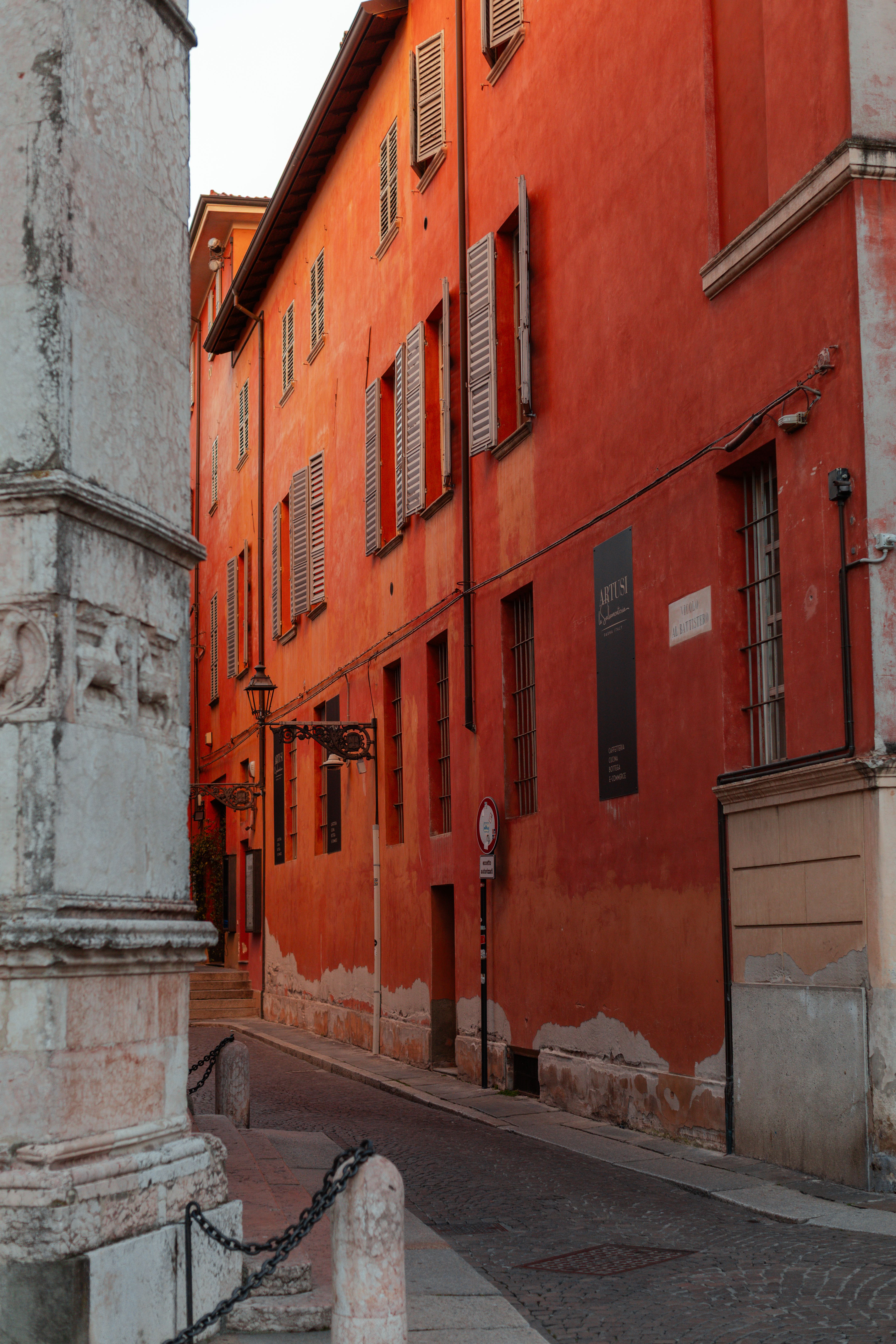 A red ochre building on a street corner in Parma