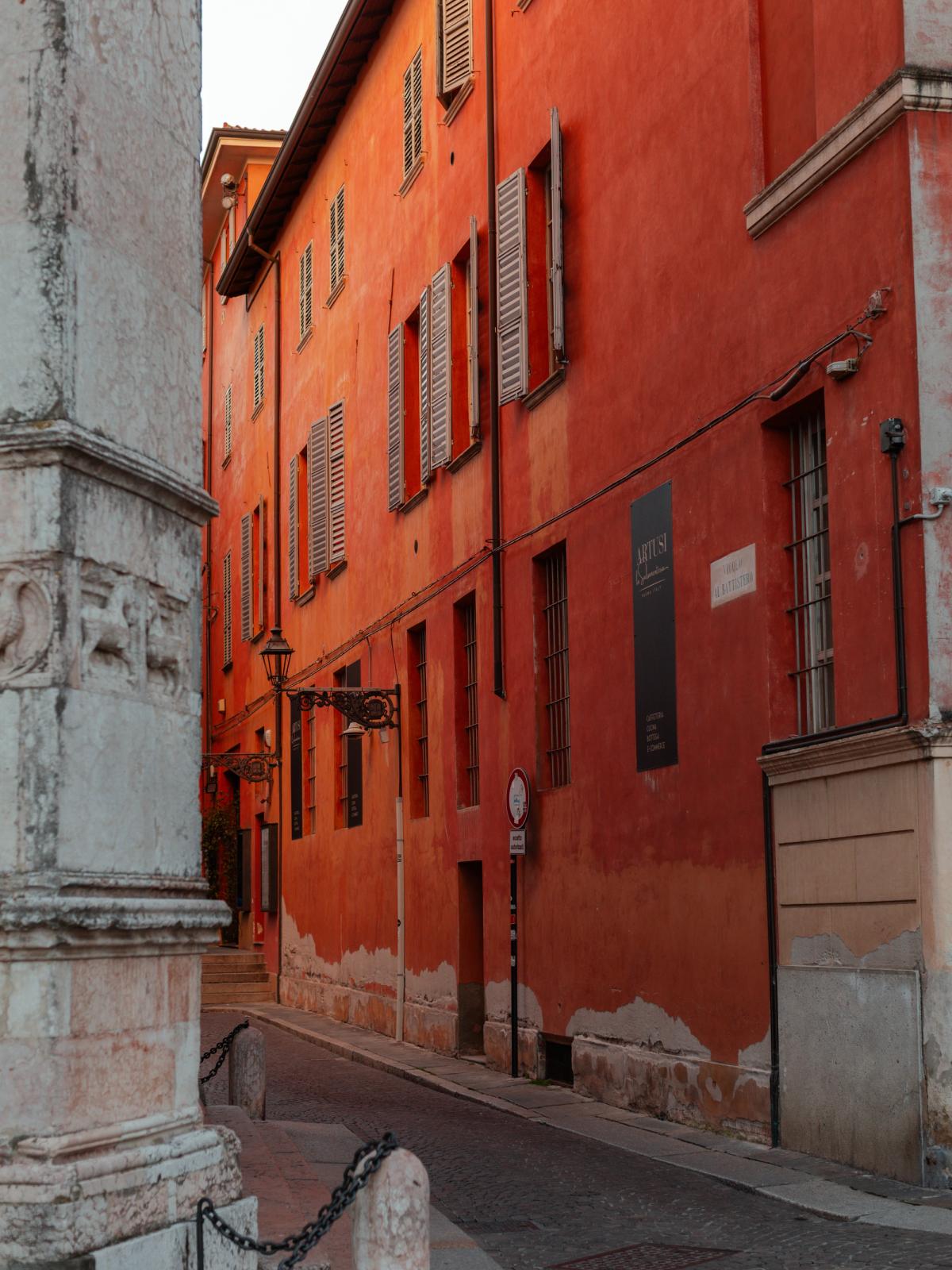 A red ochre building on a street corner in Parma