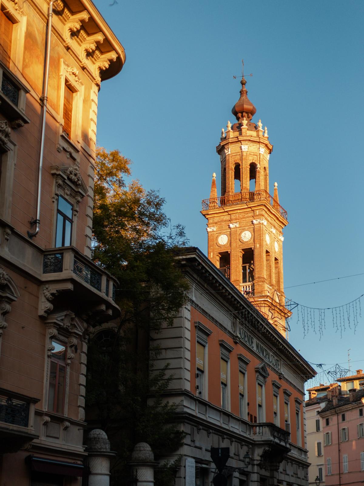 A church bell tower in Parma lit by late afternoon sun