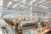Rows of industrial knitting machines on a bright factory floor