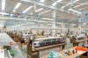 Rows of industrial knitting machines on a bright factory floor